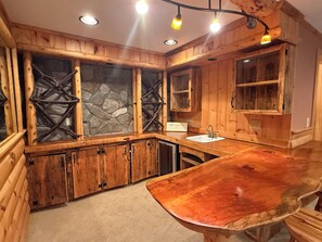 A wooden bathroom with a stone wall, a sink, and a mirror.