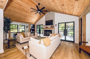 A spacious living area with a high ceiling, a fireplace, and large windows. - 
Walk to Cashiers - 2 king bed rooms + bunk bed with queen, firepit & secluded (Cashiers)