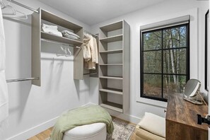 A bathroom with a built-in storage unit, a window with a view of trees, and a wooden vanity with a mirror. - 
Walk to Cashiers - 2 king bed rooms + bunk bed with queen, firepit & secluded (Cashiers)