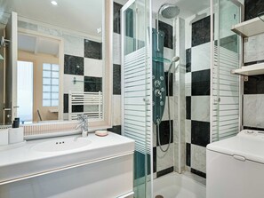 A modern bathroom with a glass-enclosed shower, a white sink, and a large mirror. - Warm Seaside Apartment - Trouville (Trouville-sur-Mer)