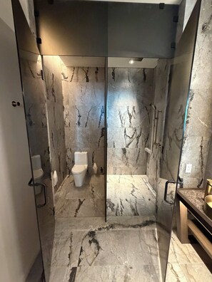 A modern bathroom with marble walls, a glass shower enclosure, and a wooden vanity. - Stunning Ocean Views 4100 sq ft condo in The Ritz-Carlton Residence (Naples)