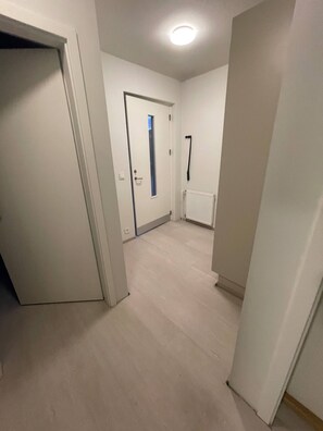A hallway with a door leading to a room, a radiator, and a window. - Cozy Apartment Near Reykjavík (Hafnarfjordur)