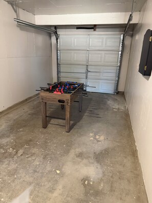 Ett garage med ett fotbollsspel i mitten, en stängd garageport i bakgrunden och ett betonggolv.