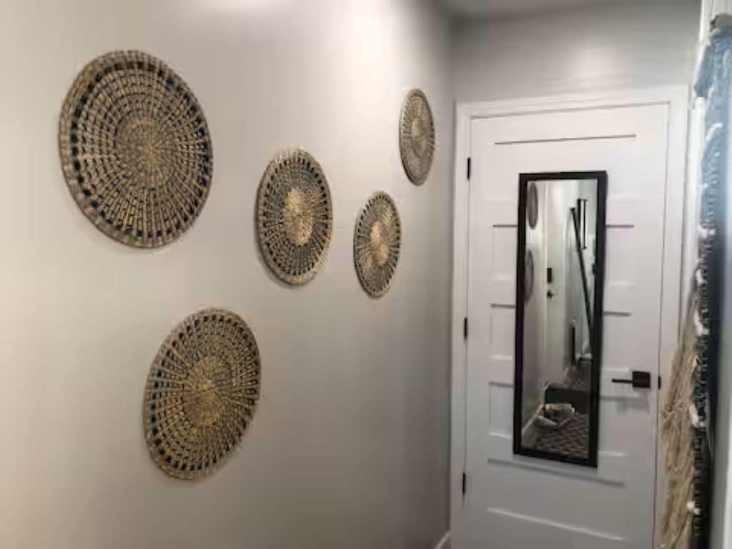 A hallway with a white door, a mirror, and four circular wall decorations.