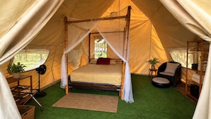 A tent with a bed, a chair, a small table, and a potted plant. - glampling sanblas luxury (Panamá)