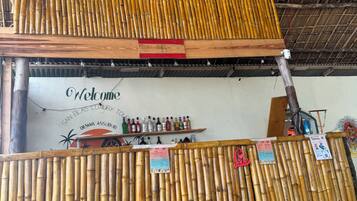 A bamboo fence, a welcome sign, and a bar area with bottles.