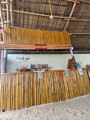 A bamboo fence, a welcome sign, and a bar area with bottles.