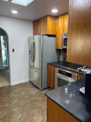 A kitchen with stainless steel appliances, wooden cabinets, and a black countertop. - Marvelous 3-bedroom house with a private pool in Albuquerque. (Albuquerque)