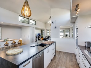 A modern kitchen with a central island, stainless steel appliances, and pendant lighting. - Napier Sea Views | Hawke's Bay (Napier)