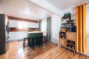 Eine moderne Küche mit weißen Schränken, einer Holztischplatte und einer eingebauten Kochinsel mit Barhocker.