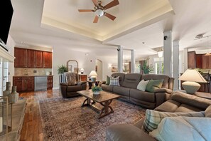 A spacious living room with a large brown leather sofa, a coffee table, and a ceiling fan. - Great Location! Fireplace! Luxury Bathrooms! (Branson)