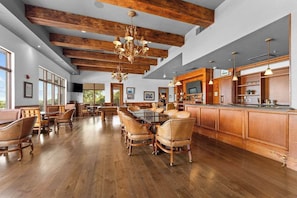 A spacious dining area with wooden beams, a chandelier, and a long wooden bar. - Great Location! Fireplace! Luxury Bathrooms! (Branson)