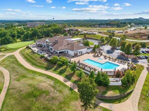 A residential area with a swimming pool, multiple houses, and a golf course in the background. - Great Location! Fireplace! Luxury Bathrooms! (Branson)