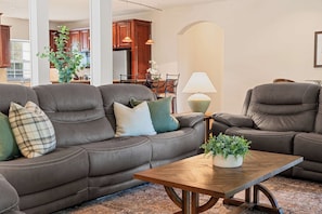 Un salon comprenant un canapé, des fauteuils, une table basse et une lampe.