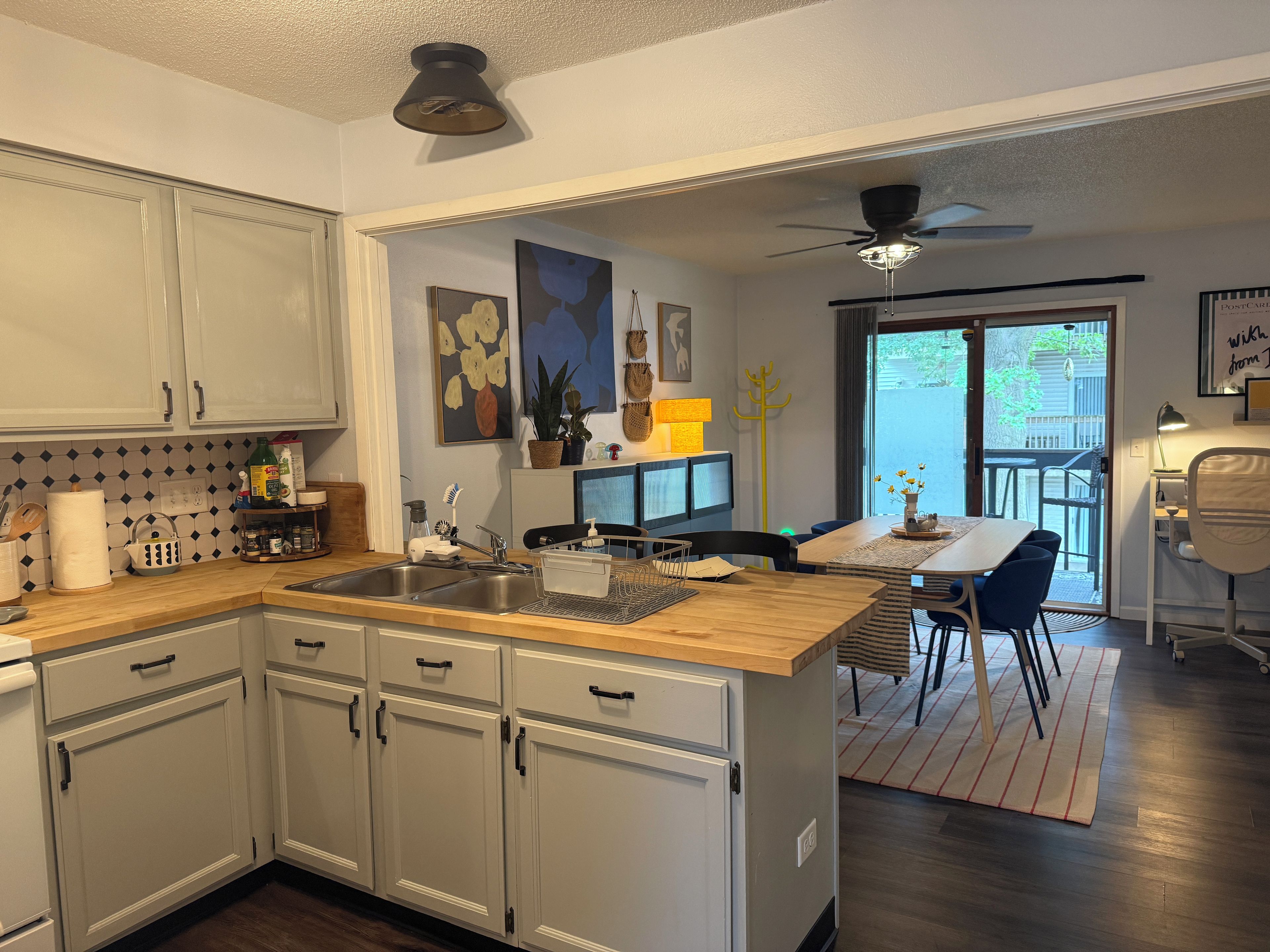 A kitchen with white cabinets, a wooden countertop, and a dining area with a table and chairs.