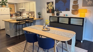 A modern kitchen with a dining area, featuring a wooden table, blue chairs, and a ceiling fan.