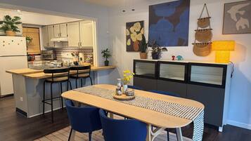 A modern kitchen with a dining area, featuring a wooden table, blue chairs, and a ceiling fan.