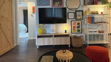 A living room with a TV, artwork, and a bookshelf.