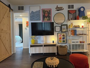 A living room with a TV, artwork, and a bookshelf.