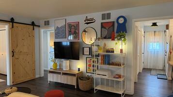A living room with a television, bookshelf, and a door leading to another room.