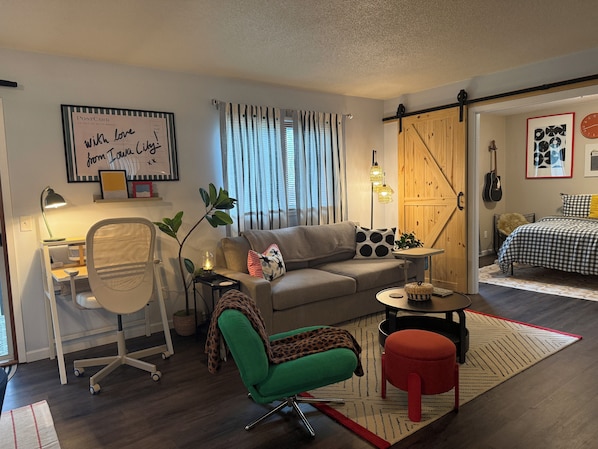 Un salon moderne comprenant un canapé, un bureau, une chaise et un coin repas avec une table et des chaises.