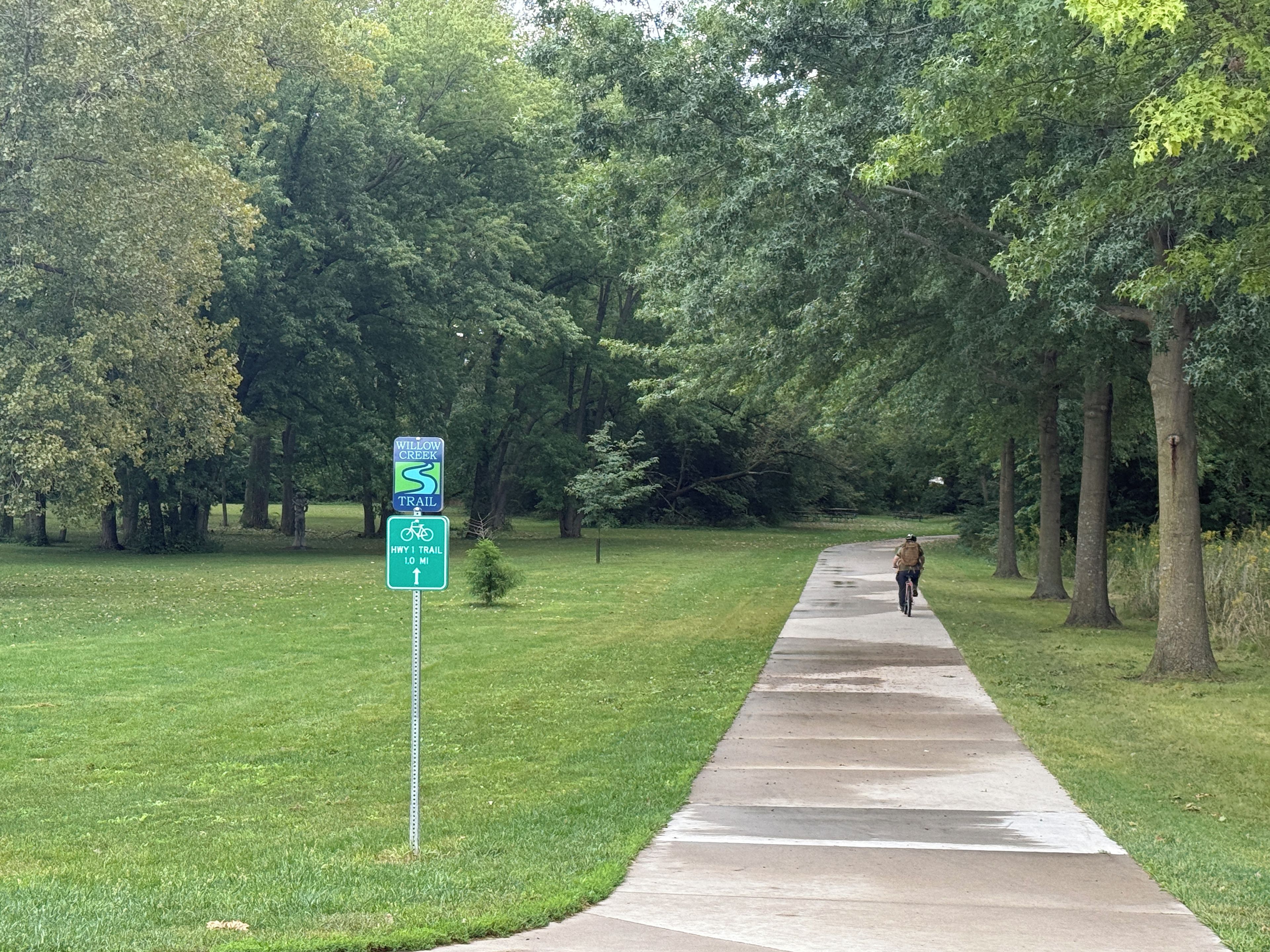 A paved walkway with a sign indicating a trail and a bike path.