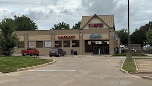 A pharmacy with a sign for HARTG drug store, a parking lot, and a red pickup truck.