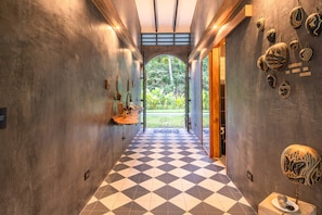 A hallway with a checkered floor, wooden beams, and decorative items on the walls. - Casa Tapa Dulce | Spacious Jungle Home with Pool (Paraíso)