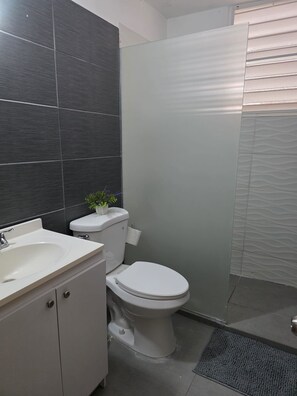 Ein modernes Badezimmer mit Waschbecken, Toilette und Dusche, alles in Weiß.