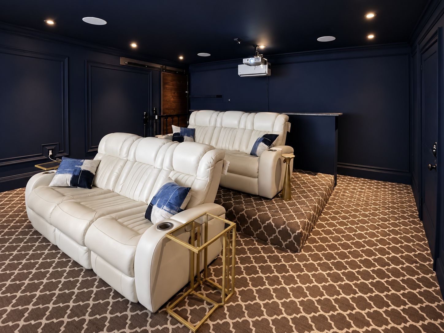 Una habitación con dos sofás reclinables, una pantalla de proyector y alfombra estampada.