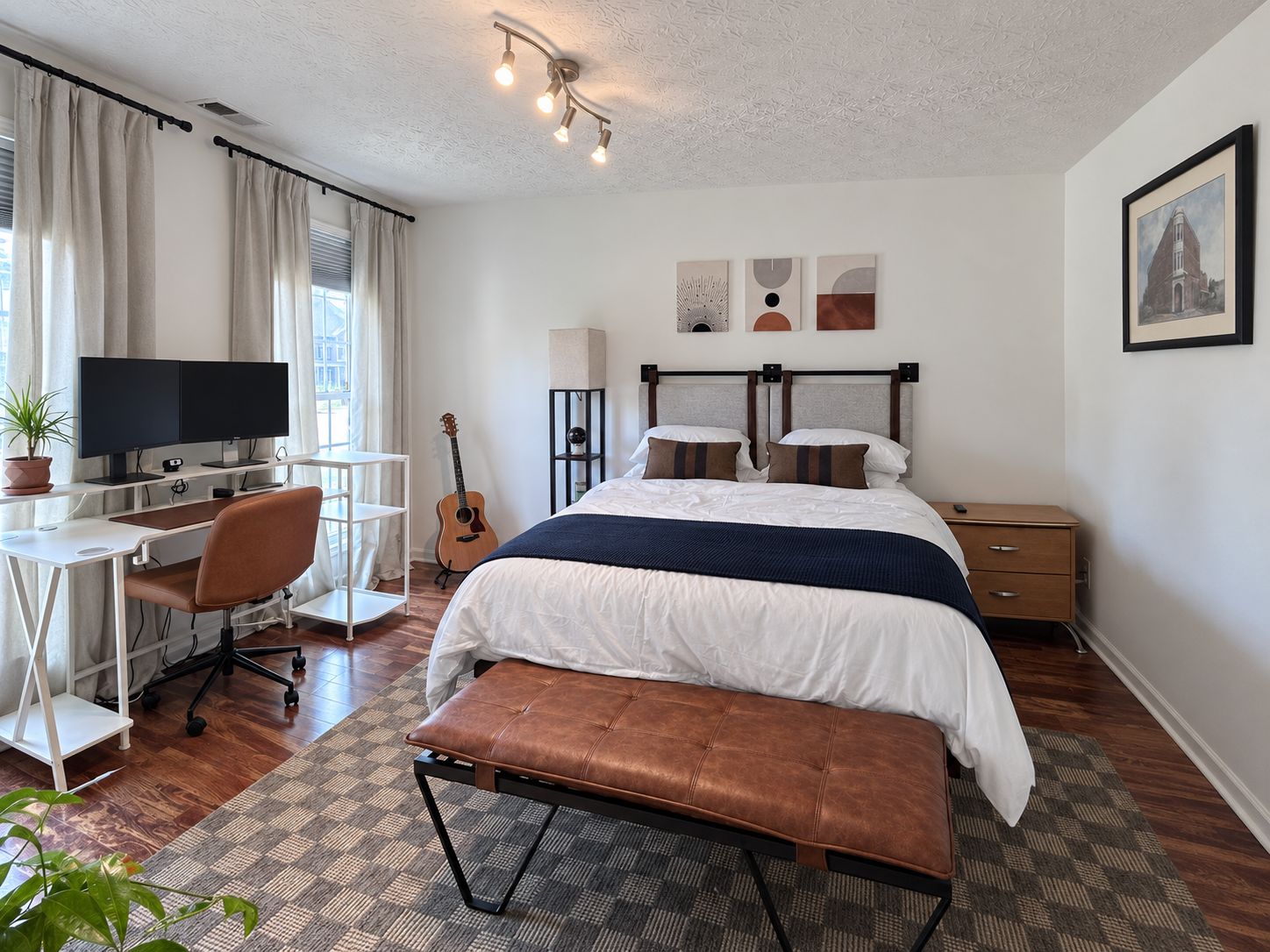 Une chambre à coucher moderne avec un lit, un bureau, une chaise et une guitare.