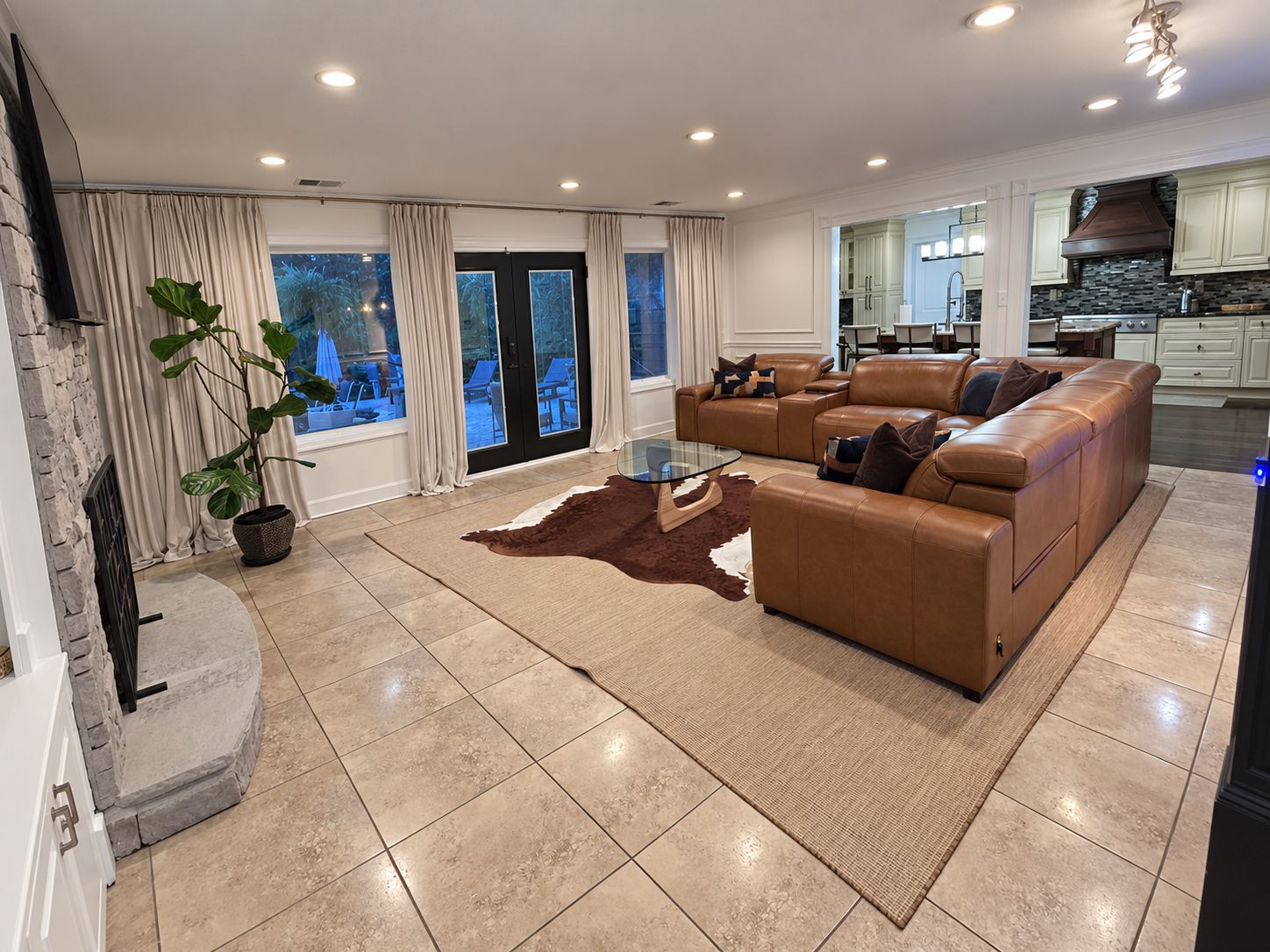 A spacious living room with a leather sofa, a glass coffee table, and a view of the outdoors.