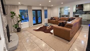 A spacious living room with a leather sofa, a glass coffee table, and a view of the outdoors.