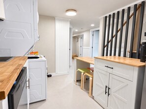 Eine Küche mit Geschirrspüler, einer Holzausziehtafel und einem Essbereich mit Stühlen.
