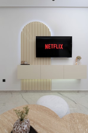 Un soggiorno moderno con una TV a schermo piatto montata a parete, un tavolino consolle minimalista e un pavimento in marmo.