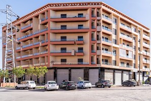 A multi-story residential building with balconies, a parking area with several cars, and a construction crane in the background. - Elegance in the heart of Marrakech / Swimming Pool (Marrakesh)