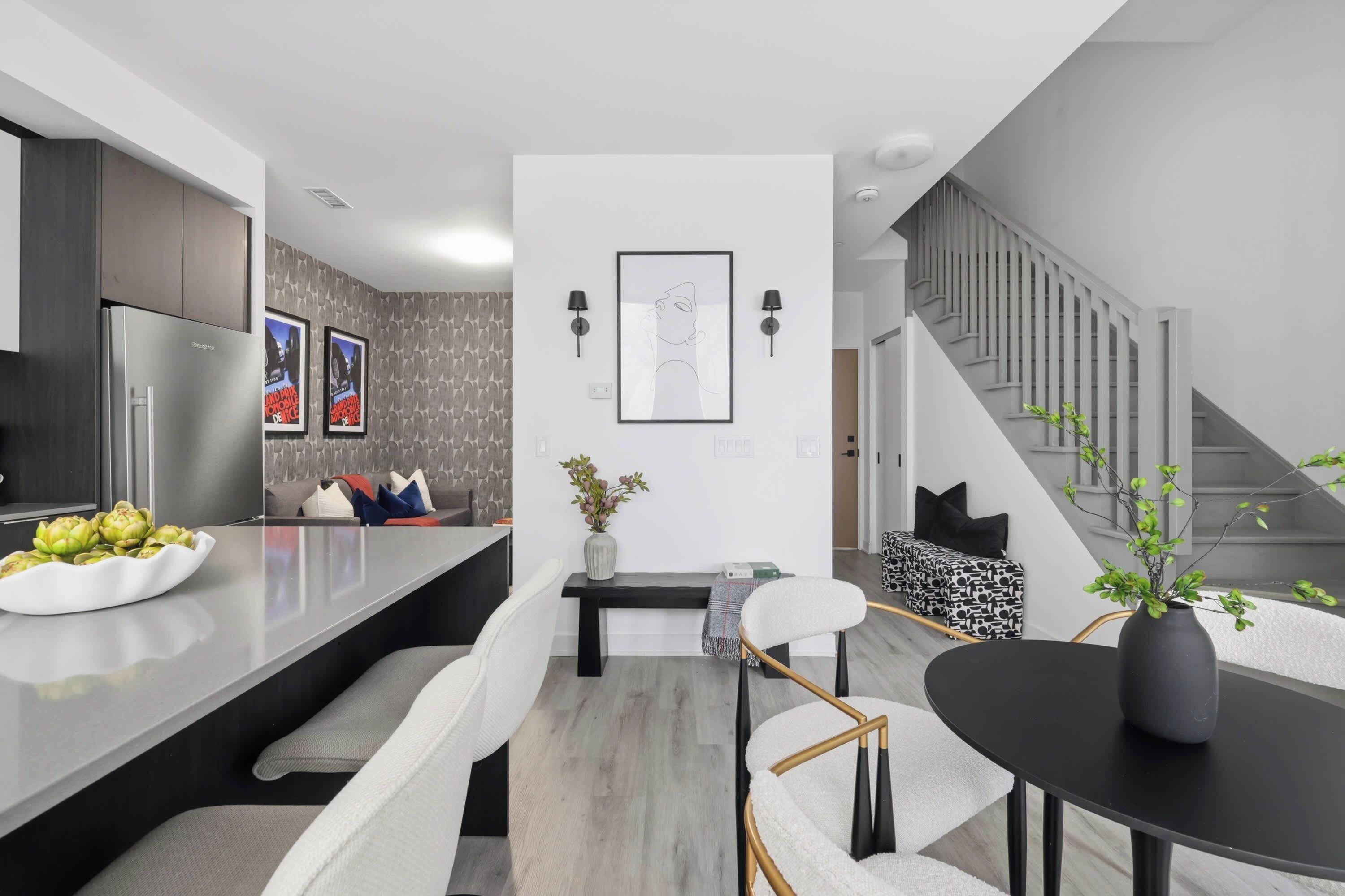 Une cuisine moderne dotée d’un îlot central, d’un coin repas et d’un escalier menant à un autre niveau.