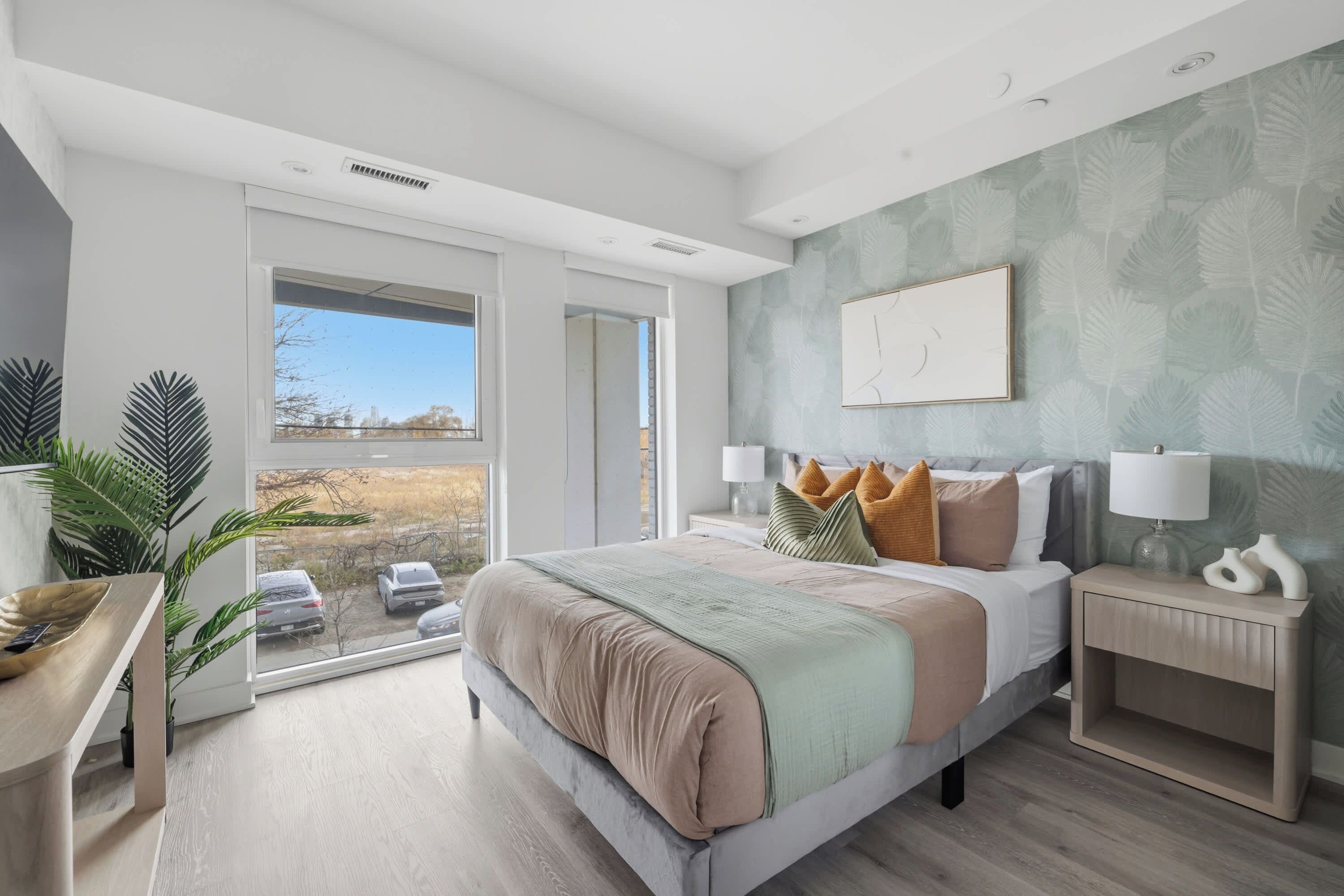 Une chambre moderne avec un grand lit, des lampes de chevet, une table de chevet et une vue sur l’extérieur, accessible par une porte coulissante.