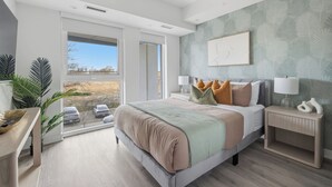 Quarto moderno com uma cama grande, luminárias de cabeceira, mesa de apoio e vista através de uma porta de correr.