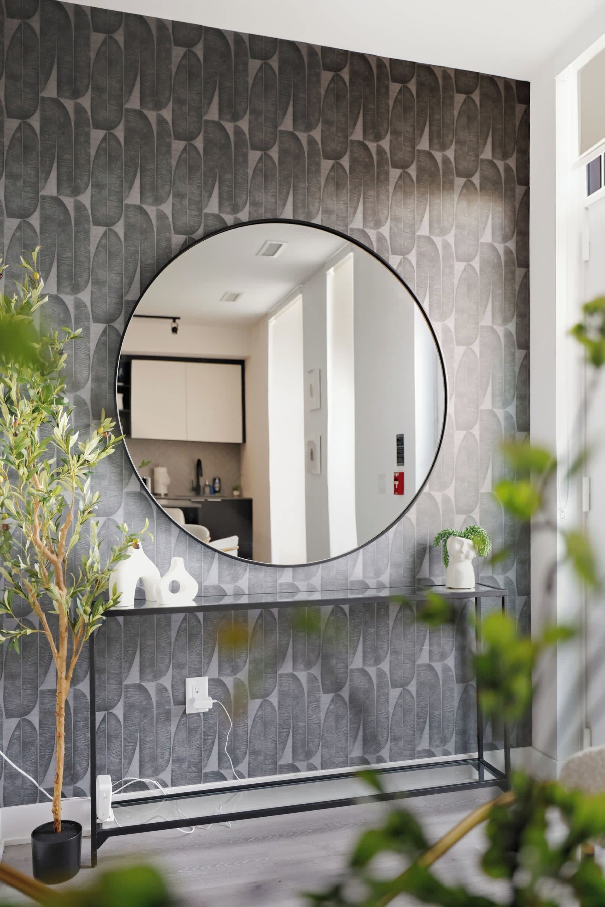 A bathroom with a round mirror, a sink, and a potted plant.