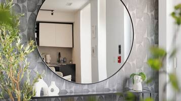 A bathroom with a round mirror, a sink, and a potted plant.