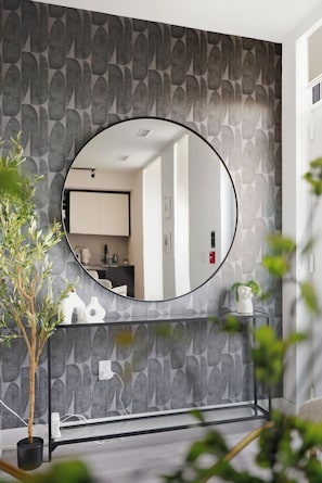 Une salle de bain avec un miroir rond, un lavabo et une plante en pot.