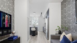 Sala de estar moderna com um sofá cinzento, televisão na parede e design minimalista.