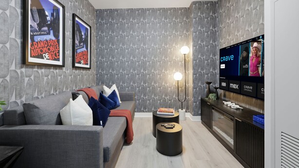 Uma sala de estar moderna com um sofá cinzento, uma mesa de centro, uma TV sobre um suporte e cartazes emoldurados na parede.