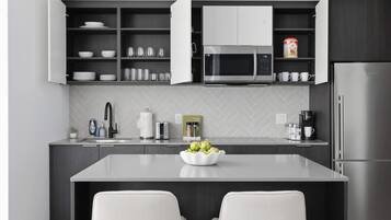 A modern kitchen with a central island, a microwave, a coffee maker, and a refrigerator.