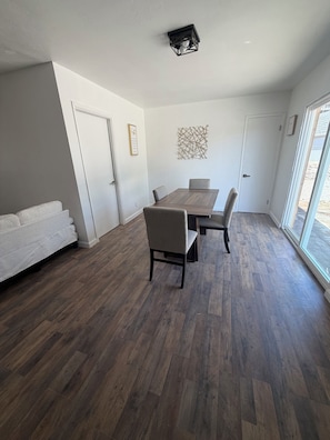Ein modernes Interieur mit einem Esstisch, Stühlen, einer Couch und einer Wanddekoration.