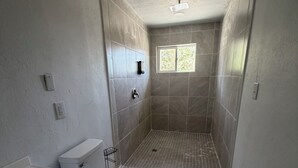 Un baño con inodoro, lavamanos y zona de ducha.