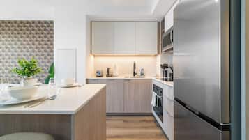 Una cocina moderna con una isla central, electrodomésticos de acero inoxidable y acabados en madera clara.