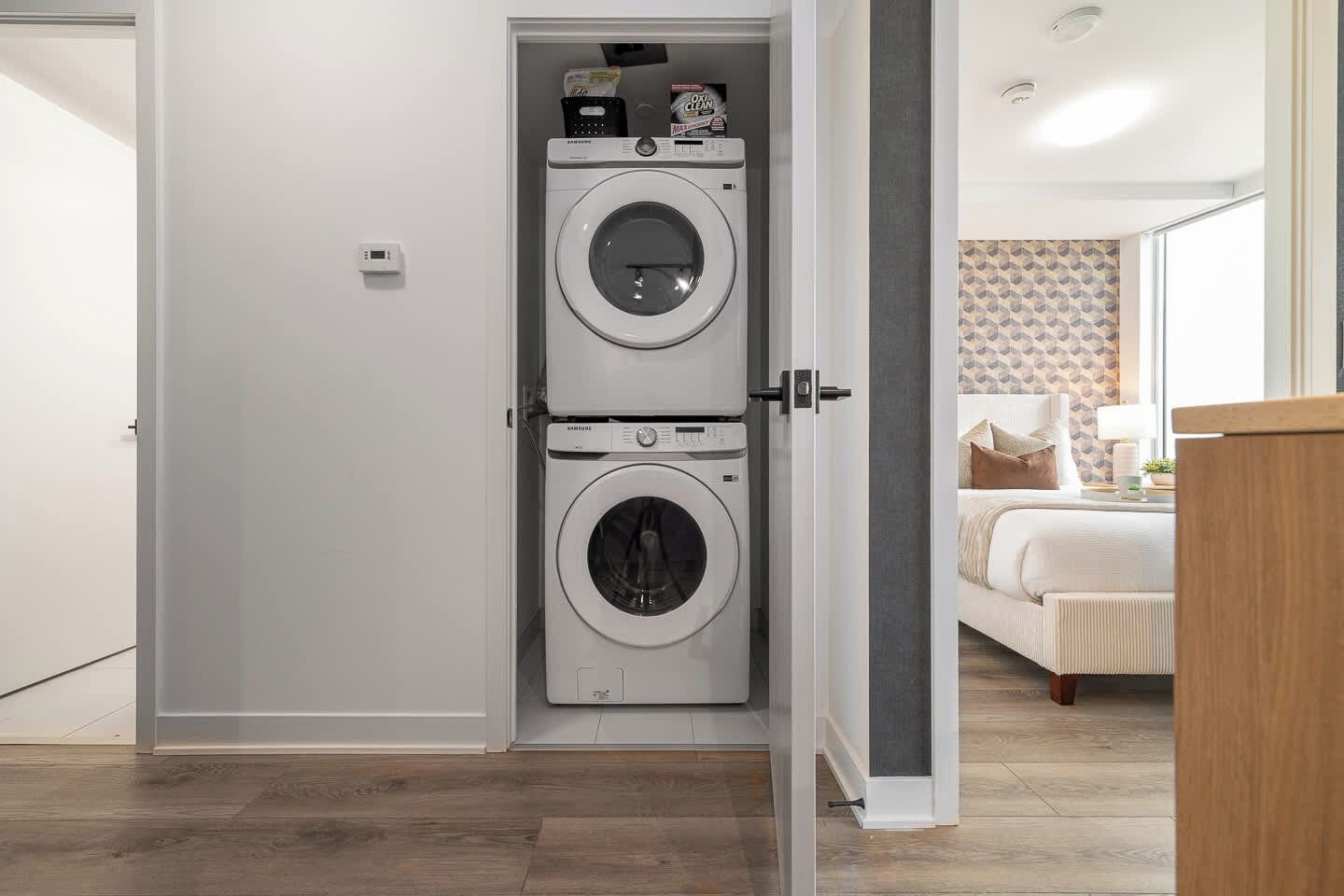 A laundry room with two stacked washing machines and a small shelf with cleaning supplies.