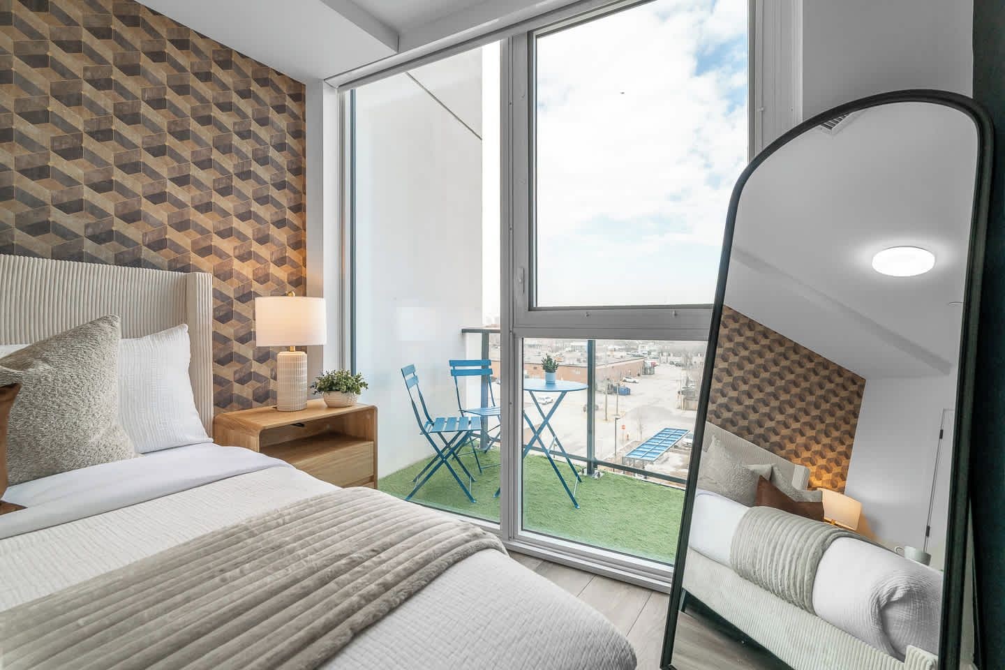 A hotel room with a bed, a desk, a chair, a balcony with a view, and a window.